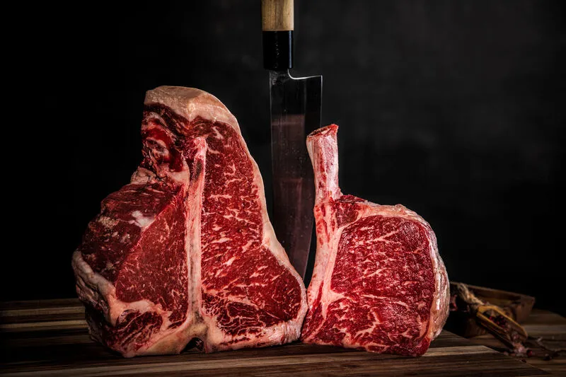 A thick-cut cowboy ribeye resting on a wooden board